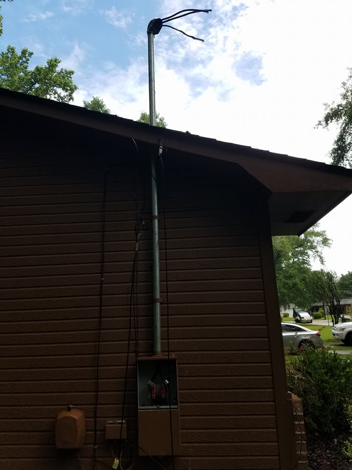 Side of a brown building with a utility pole, electrical meter, and roof against a blue sky