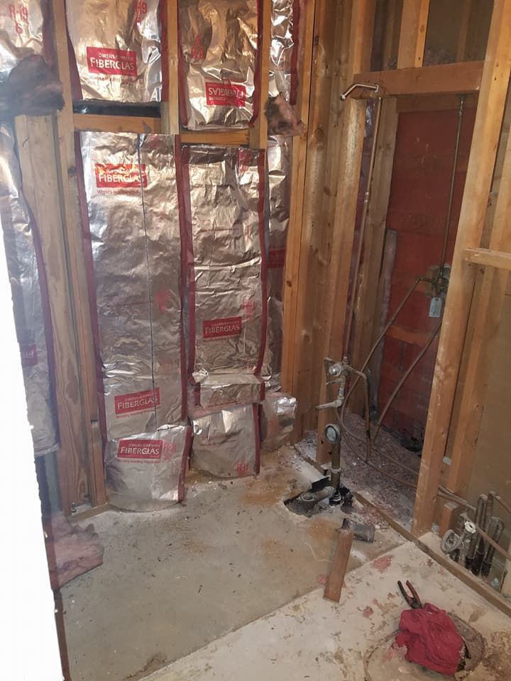 Partially insulated wall framing in a construction site with exposed studs and wiring.
