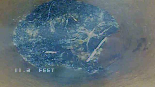 Blue debris clogging a round pipe, with 
