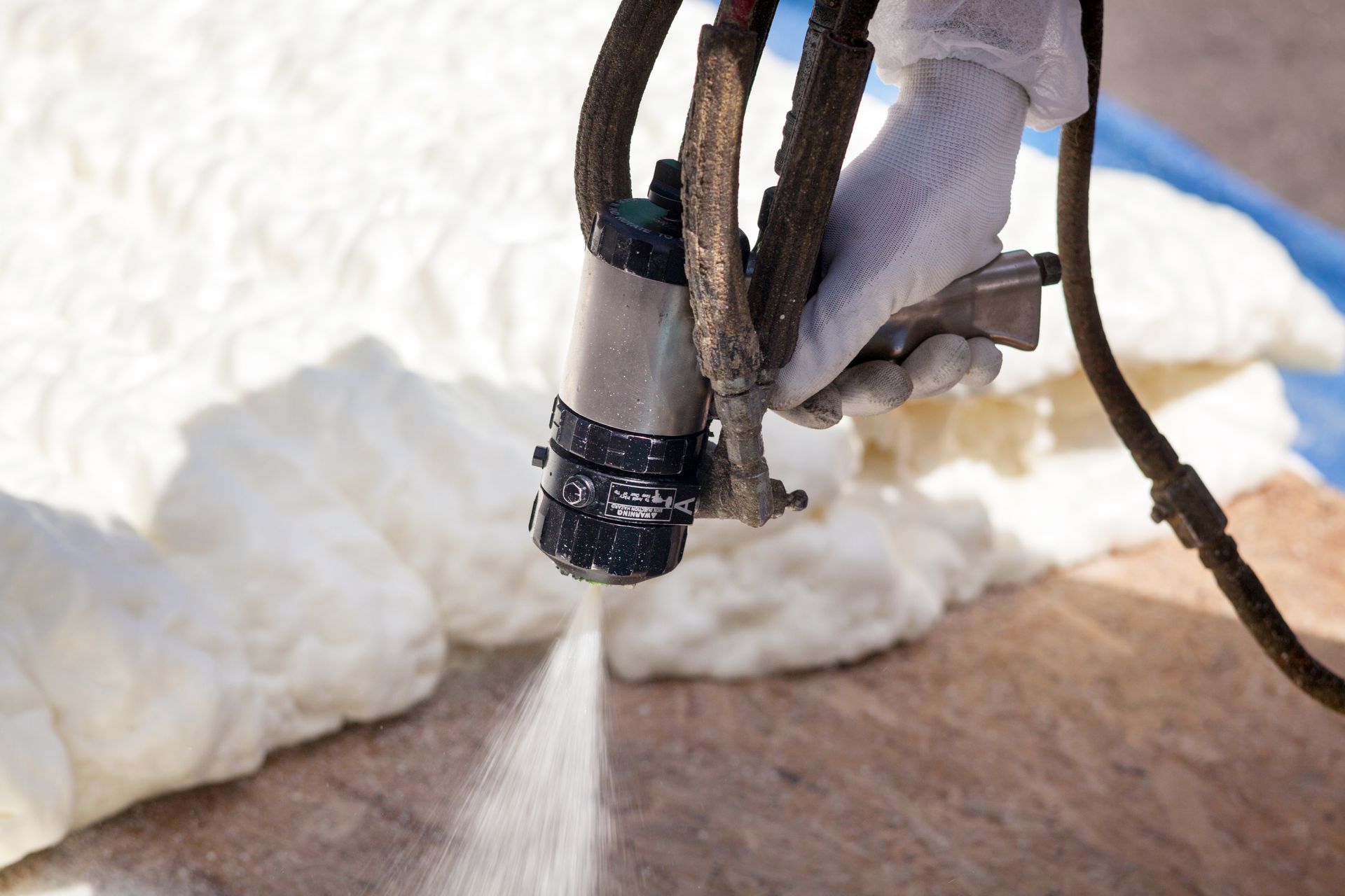 Technician spraying foam insulation using a plural component spray gun.