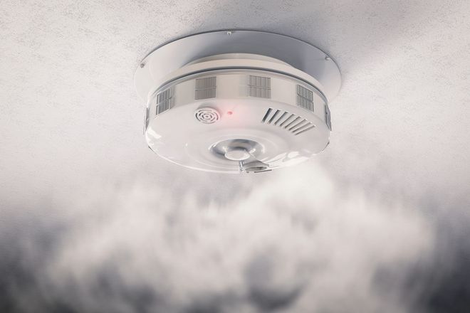 Rilevatore di fumo sul soffitto da cui fuoriesce fumo.
