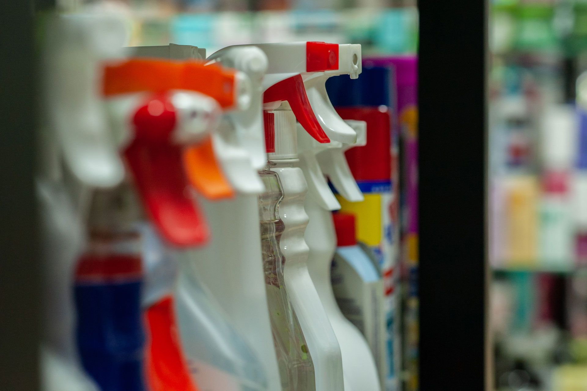 White spray bottles with red and orange triggers, in a store display.