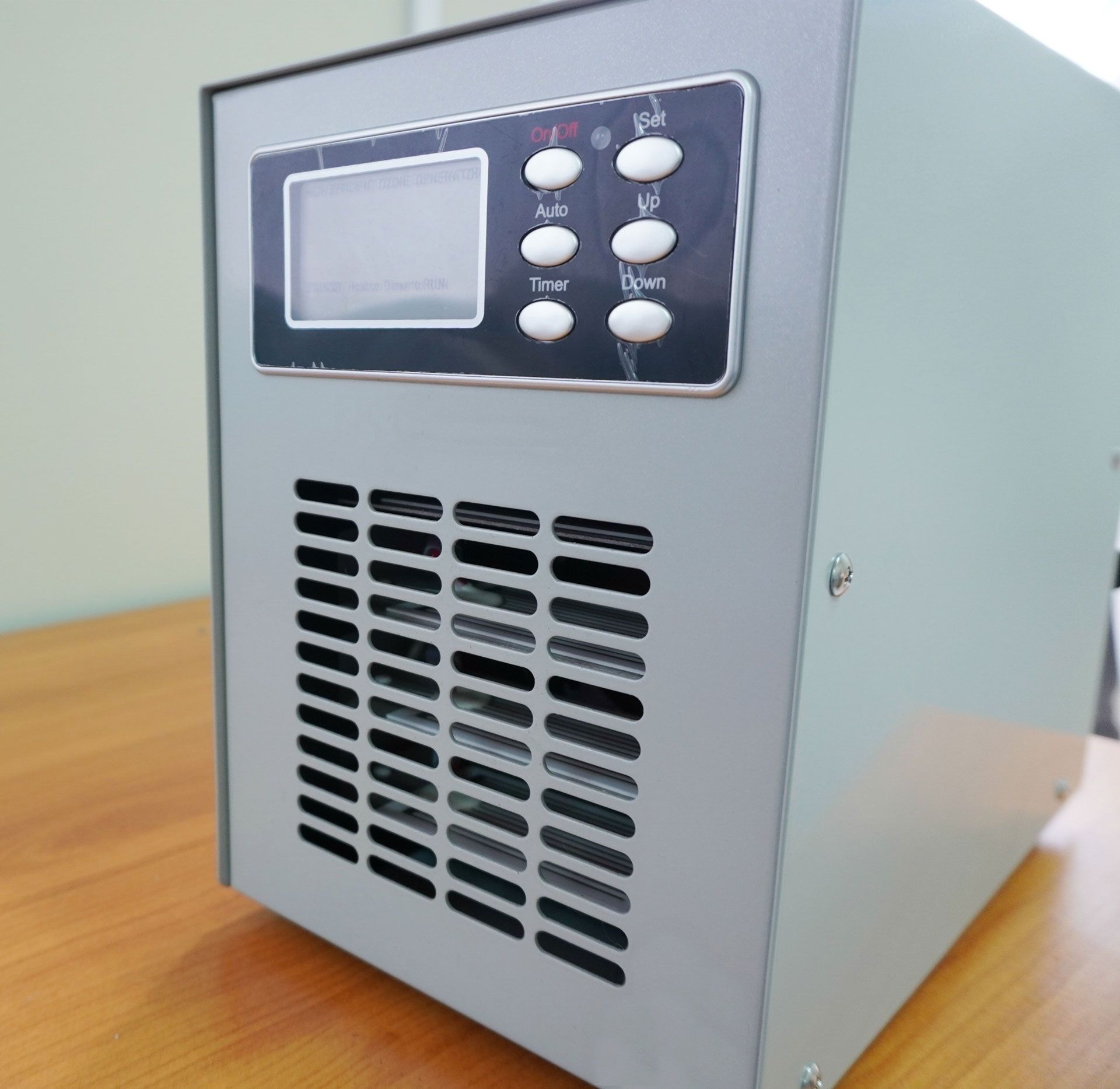 Gray electrical device with display and buttons, ventilation grill on the front.