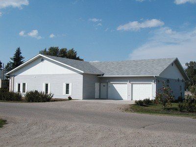 White house with attached garage on a gravel driveway under a blue sky