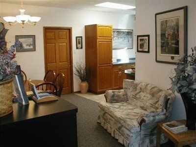 Small living room with floral sofa, dark desk, wooden cabinet, and ceiling light