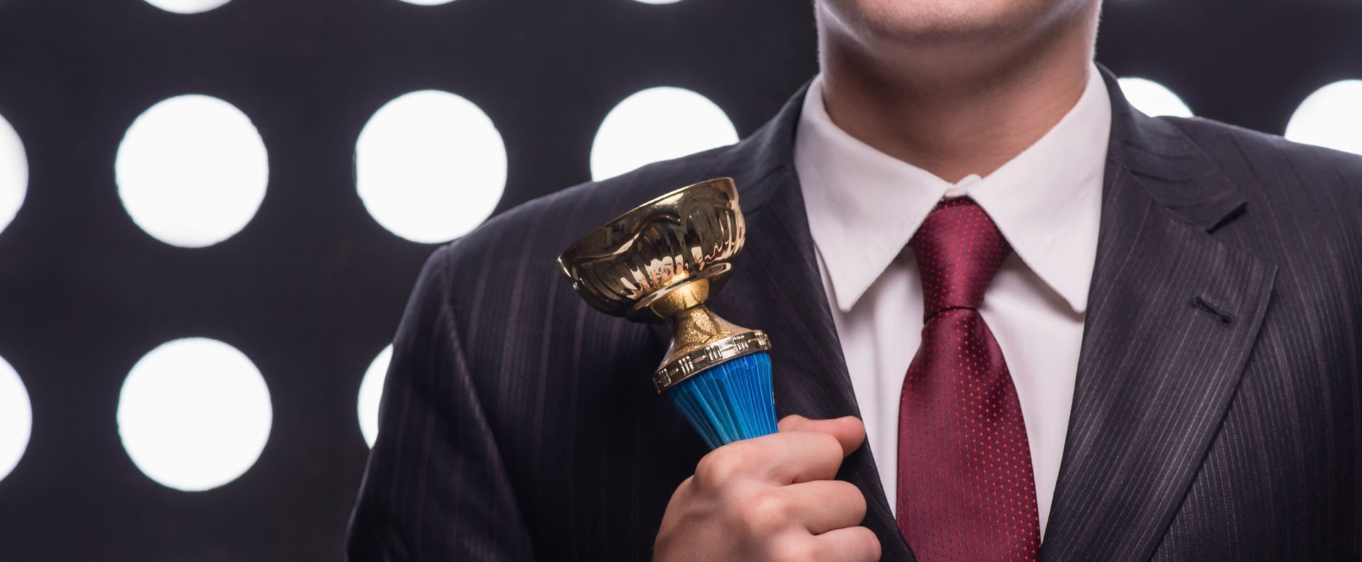 A man in a suit and tie is holding a trophy.
