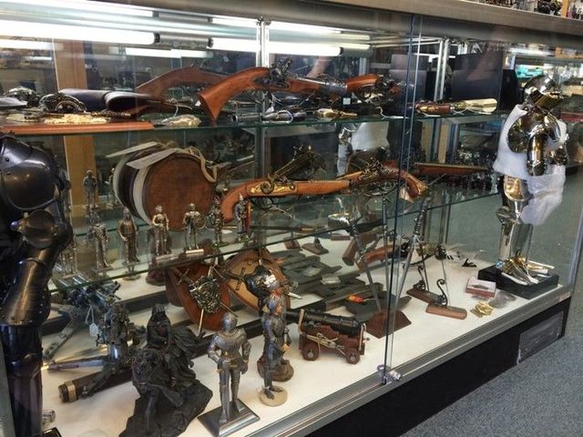 Display of historical armour and weapons in a glass case.