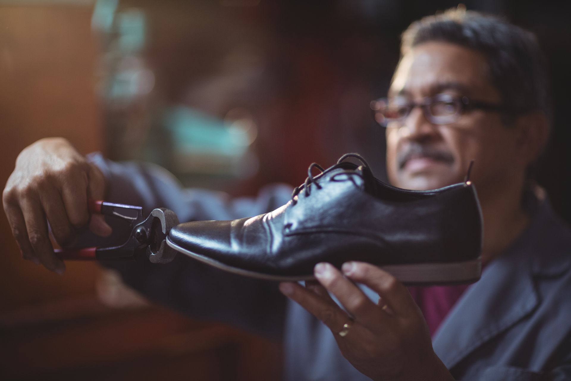 A man is holding a pair of black shoes in his hands.