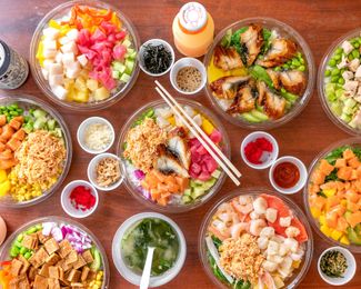Colorful assortment of Asian dishes and bowls arranged on a wooden table, with chopsticks and sauces