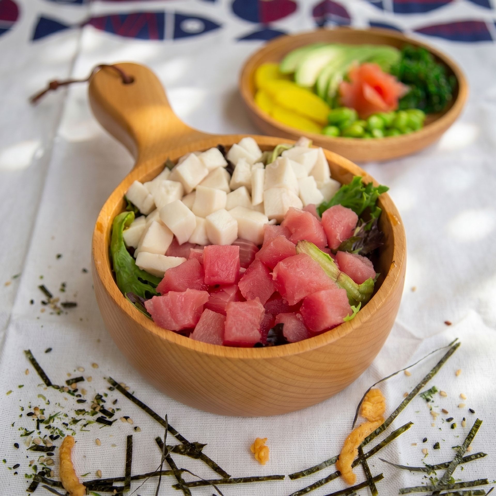 Wooden bowls of diced watermelon and tofu with greens on a light tablecloth