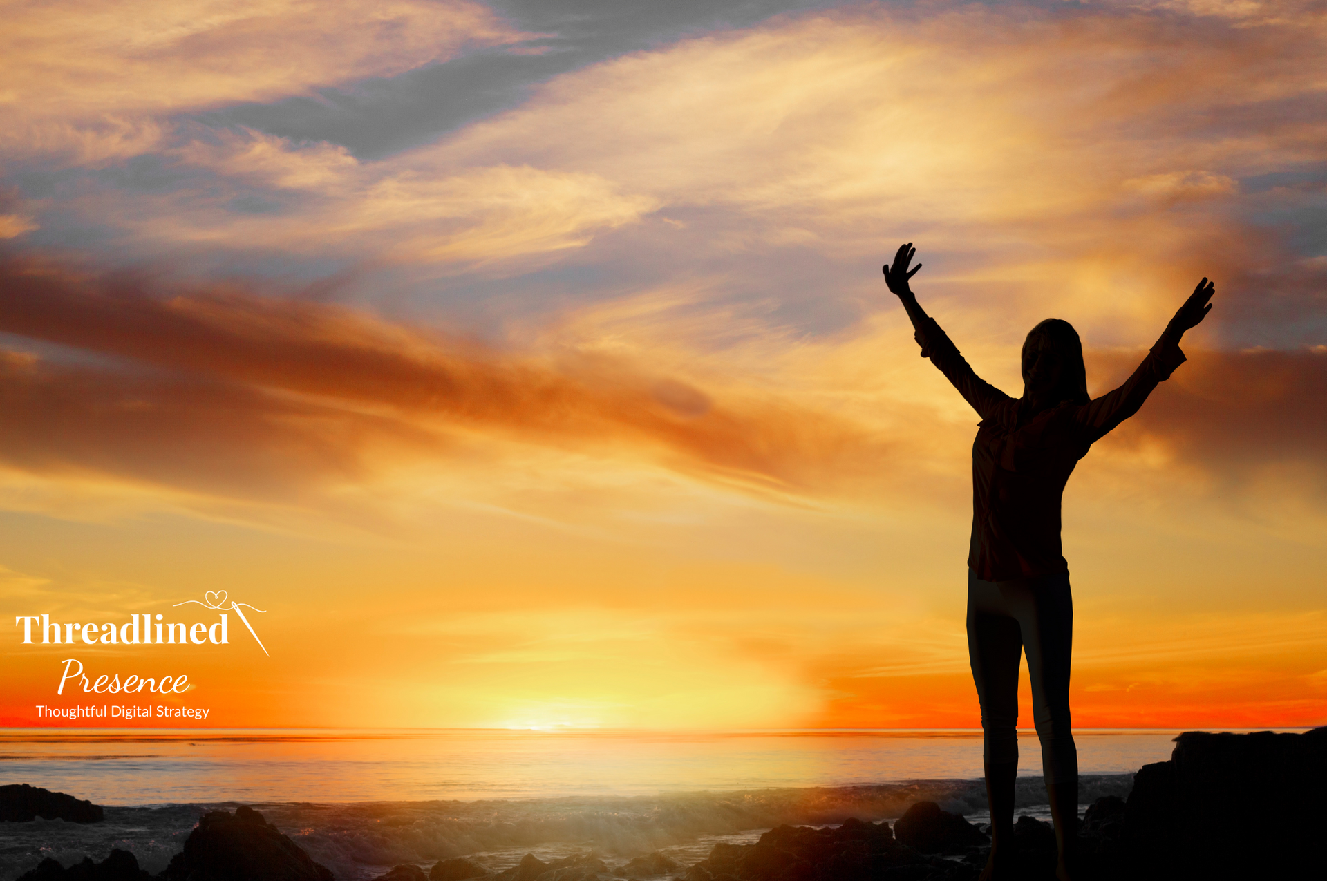 A woman overlooking the sunrise on a beach with her arms in the air in a freeing fashion