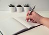 a bright desk with plants in the background and person taking notes, depicting the planning stage.