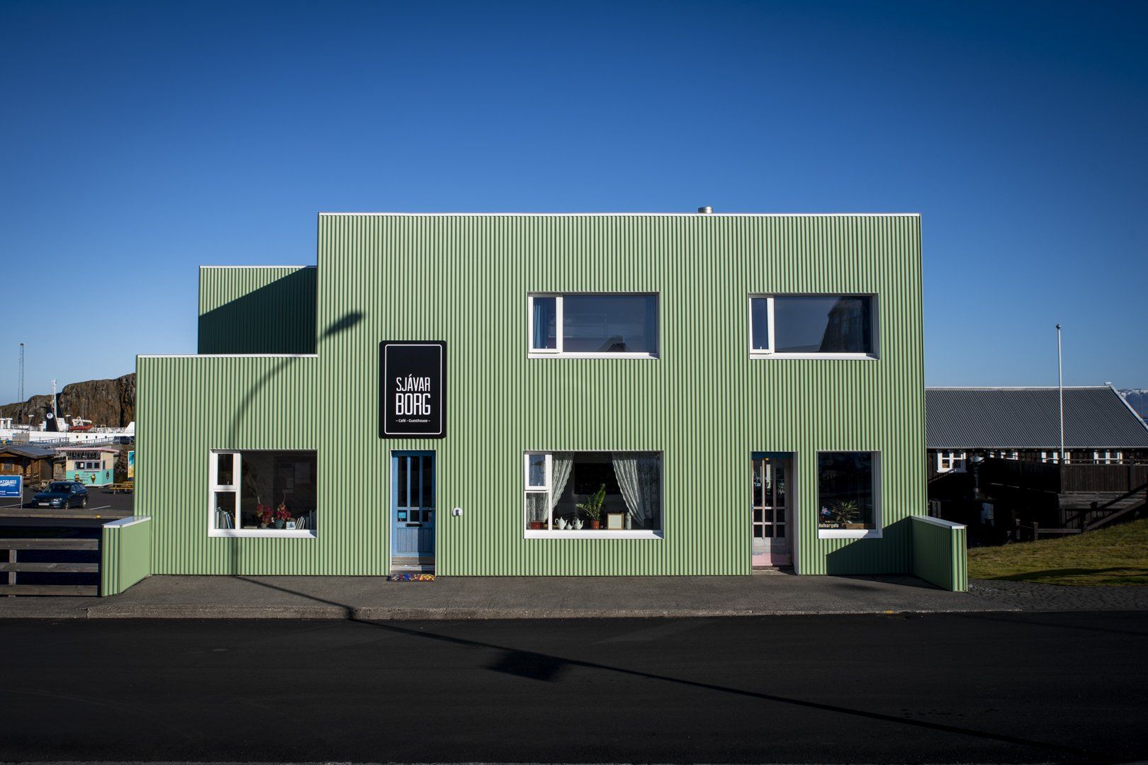 A green building with a lot of windows and a blue sky in the background.