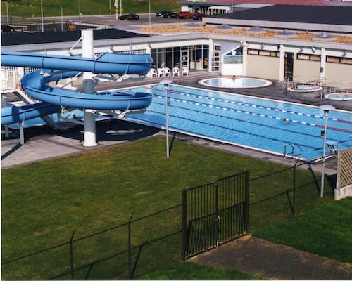 A large swimming pool with a water slide in the background