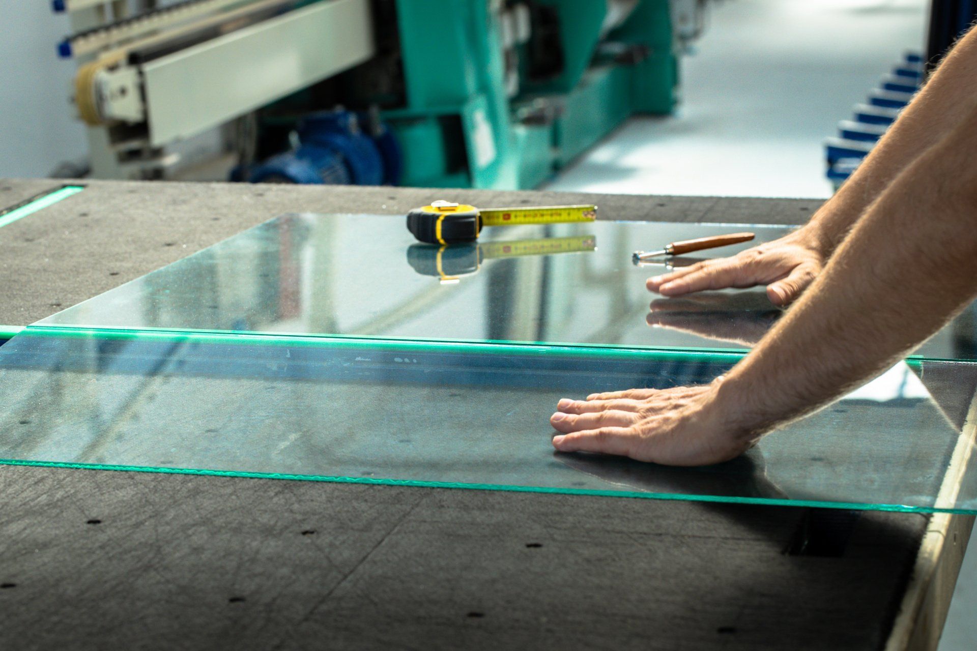 Un homme coupe un morceau de verre sur une table.