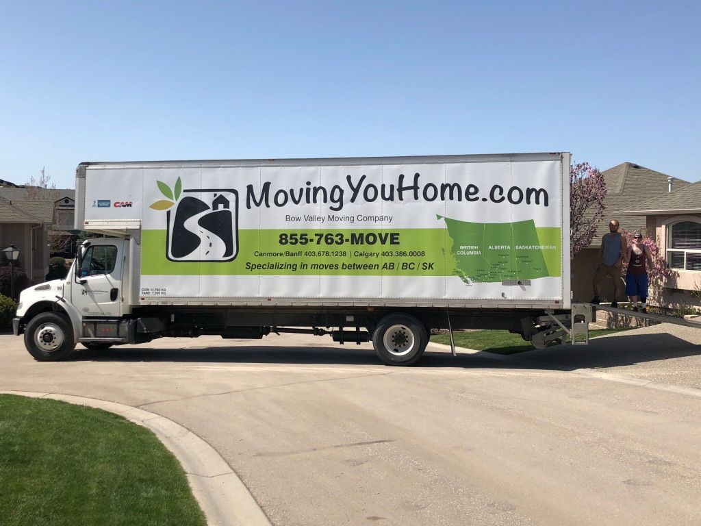 MovingYouHome.com moving truck parked on a sunny street with a curved driveway nearby