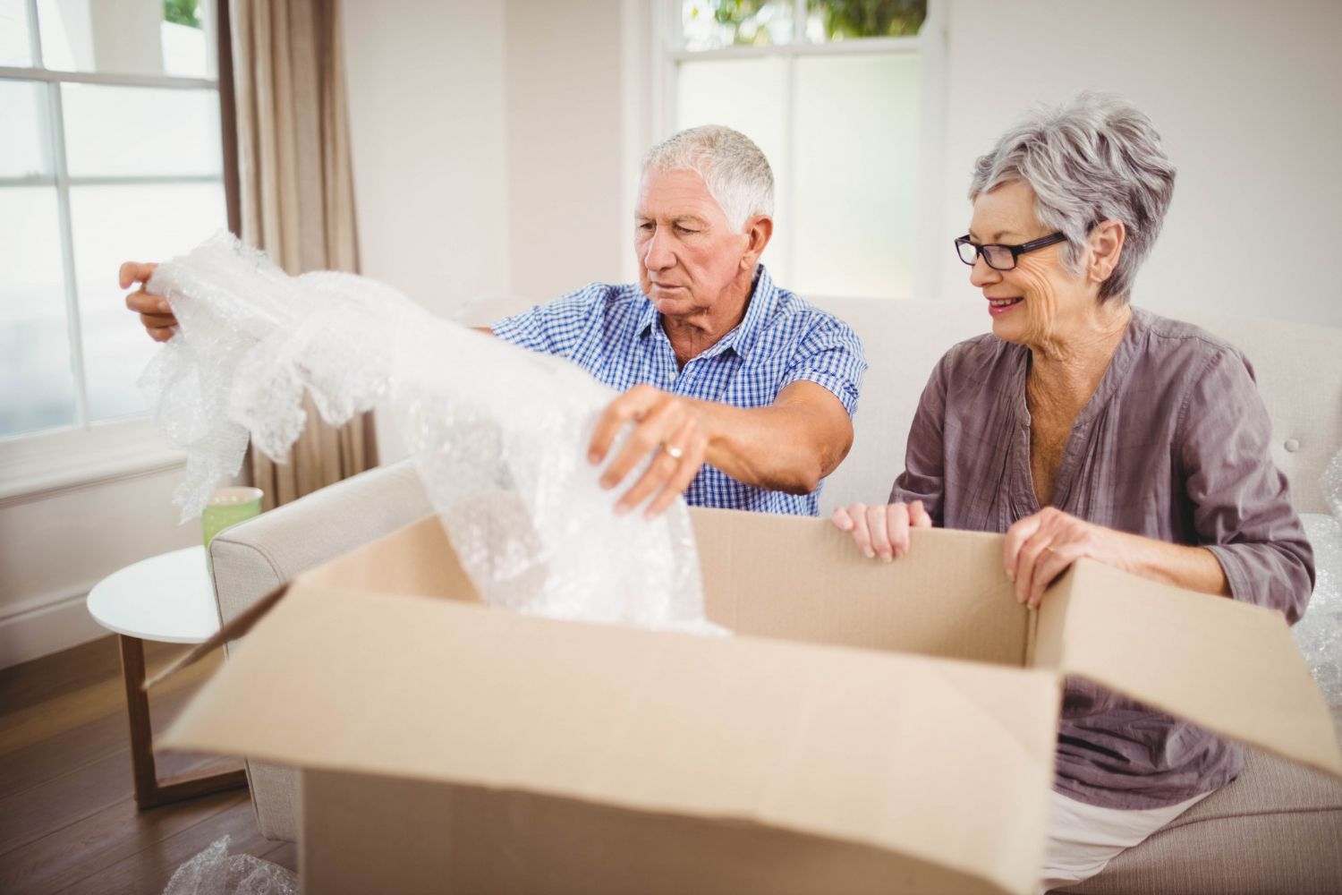 Two adults unpacking a large box in a bright living room