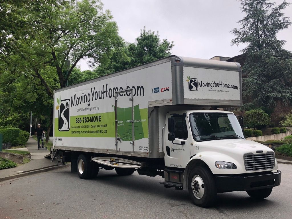 A white moving truck is parked on the side of the road.