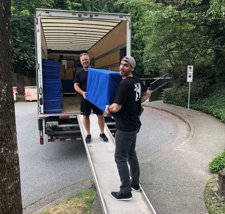 Two men are loading boxes into a moving truck.