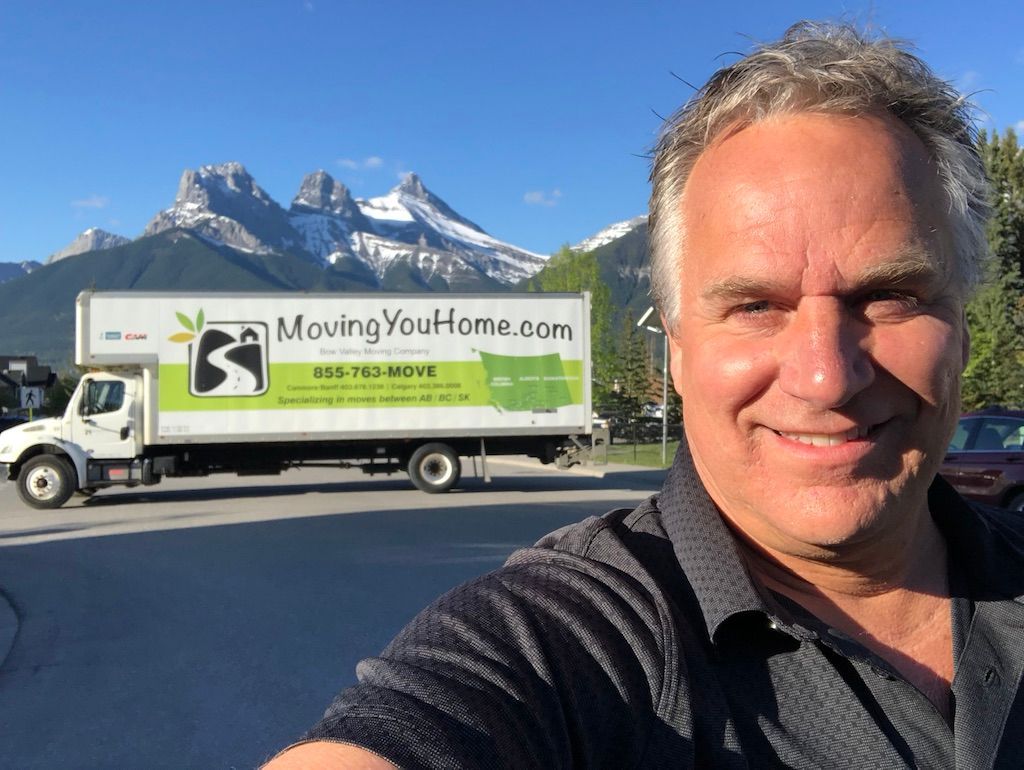 A man is taking a selfie in front of a moving truck.
