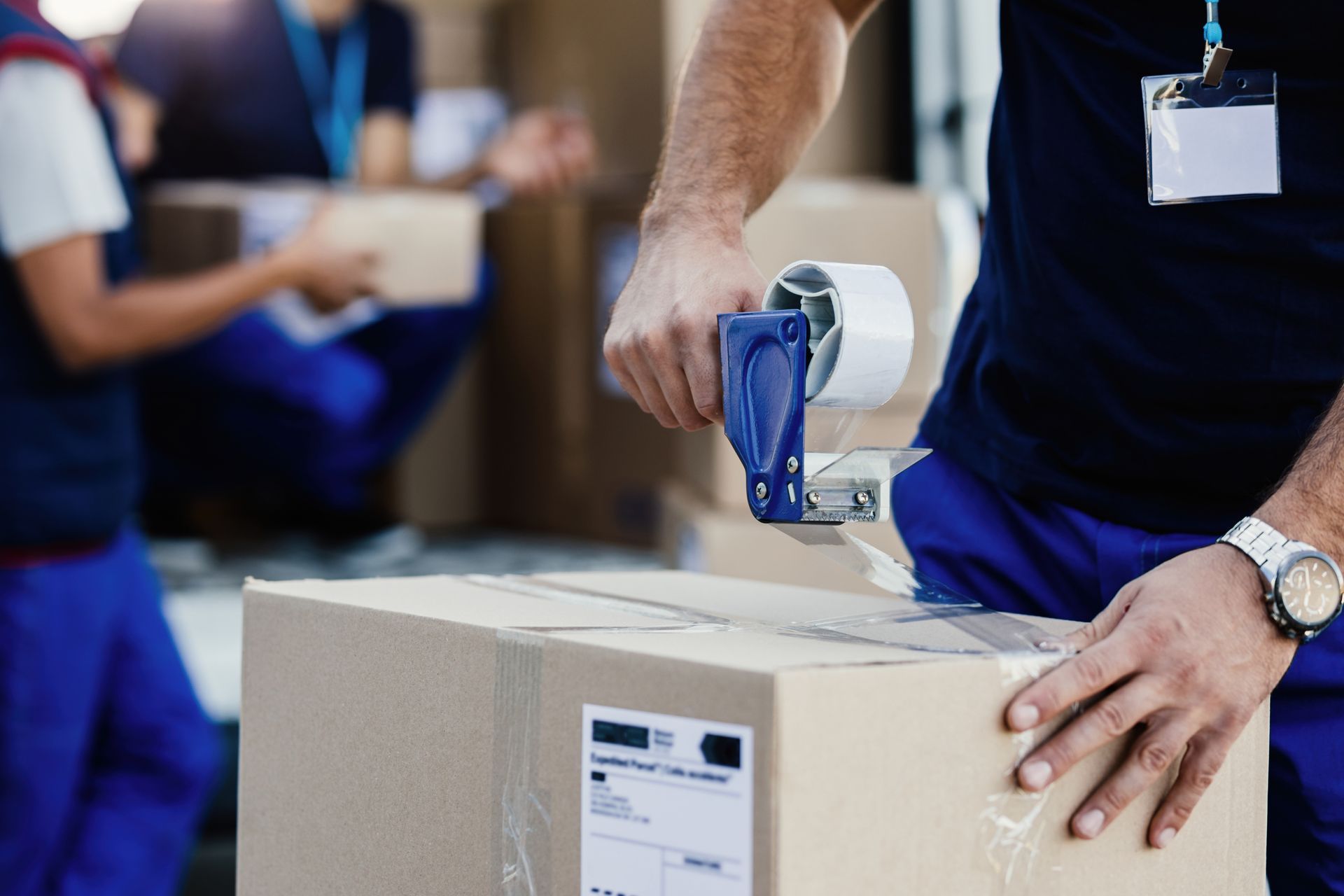 A man is taping a cardboard box with tape.