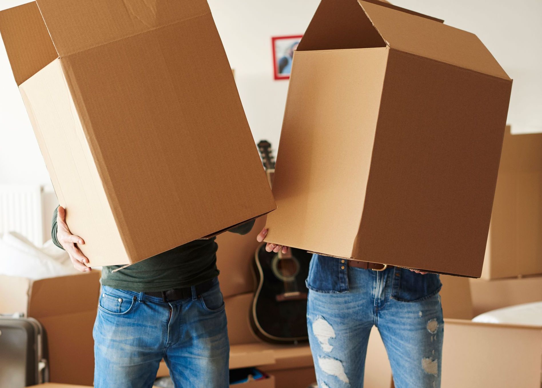 Two people are holding cardboard boxes over their heads.