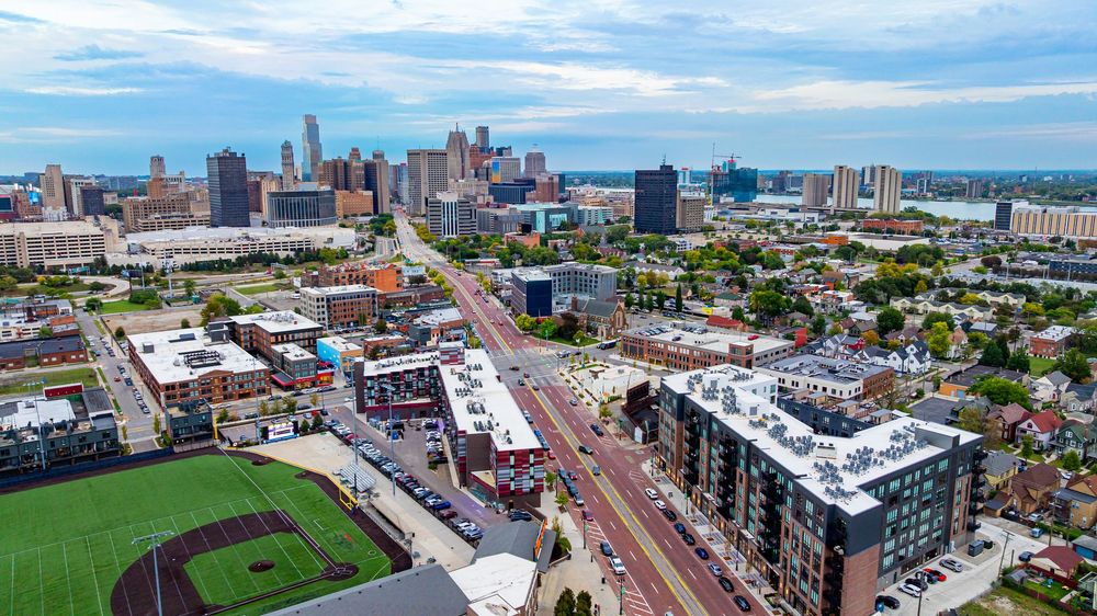 Aerial view of a city skyline with streets, buildings, and a baseball field in the foreground.