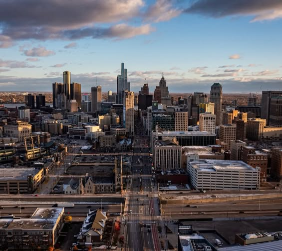 Aerial view of a city skyline at sunset with tall skyscrapers and highways in the foreground