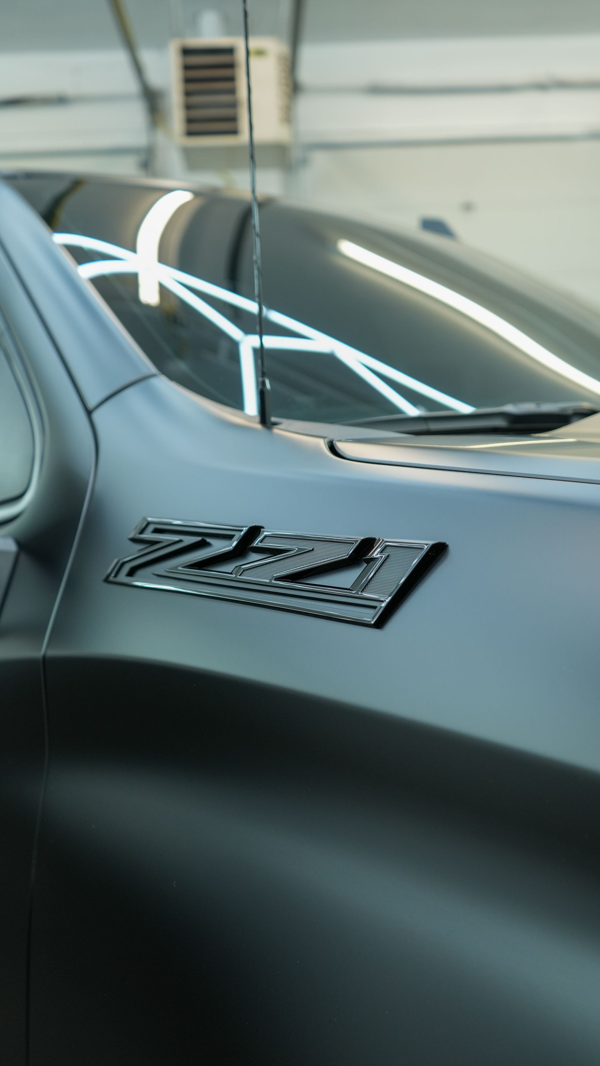 Glossy hood reflecting the shop lighting after paint correction