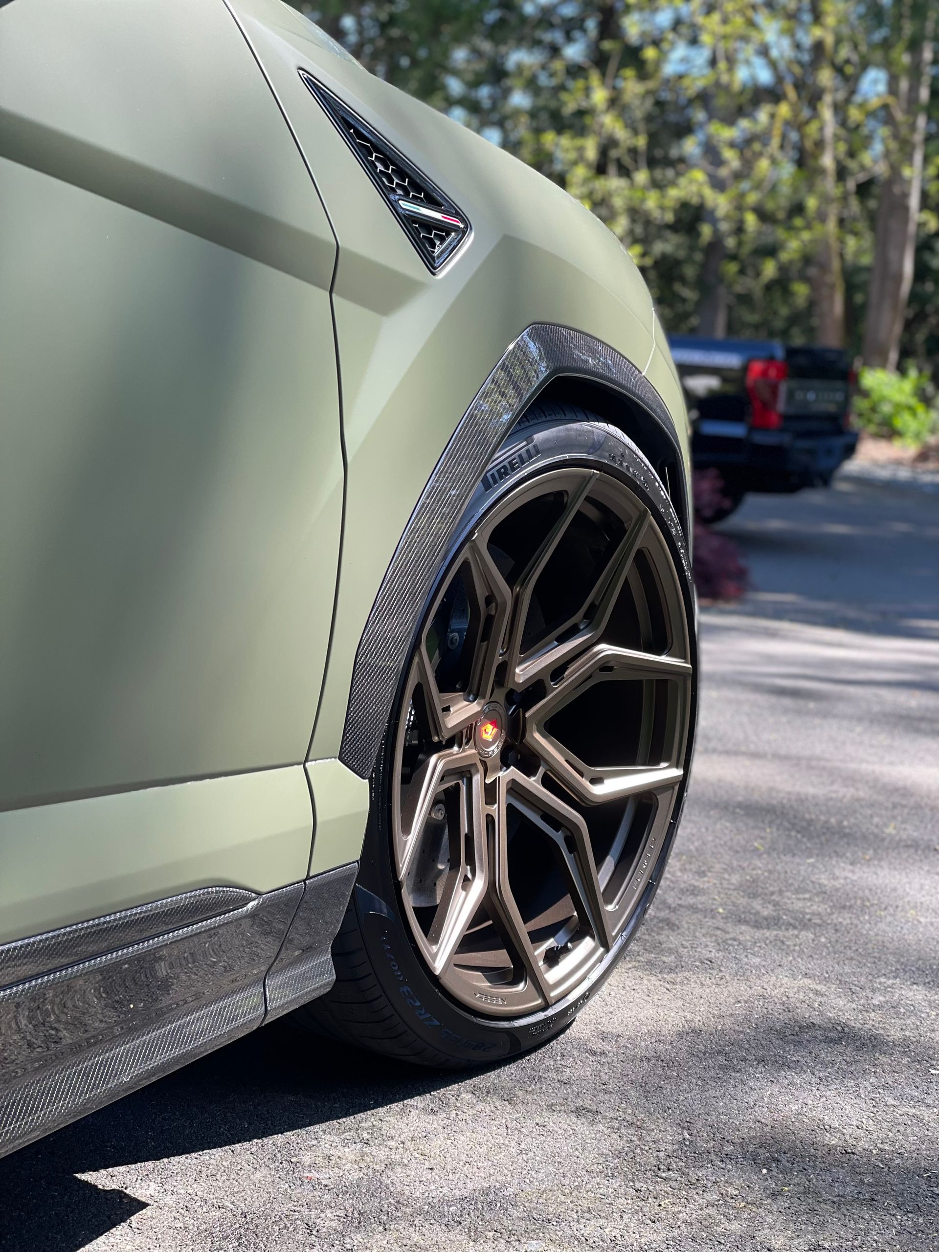 Matte green Lamborghini Urus wheel and carbon fender detail after ceramic coating