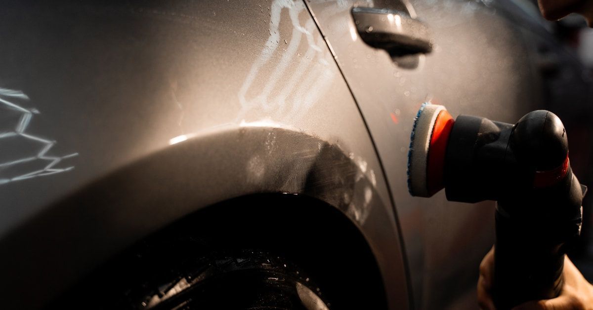 A deep paint correction to get scratches out of the car's exterior. A person is running a buffer over the car door.