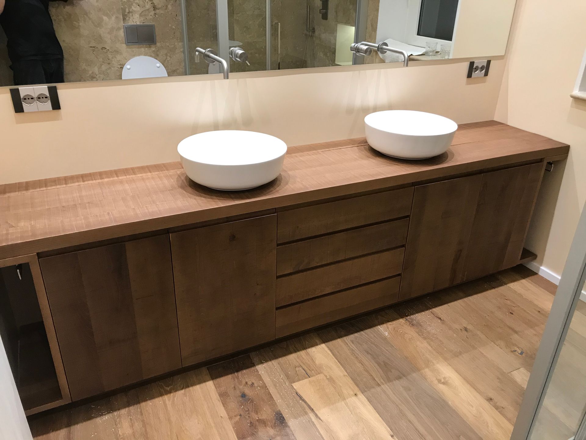 Mobile bagno moderno con due lavabi a ciotola bianchi, ante in legno e un grande specchio.