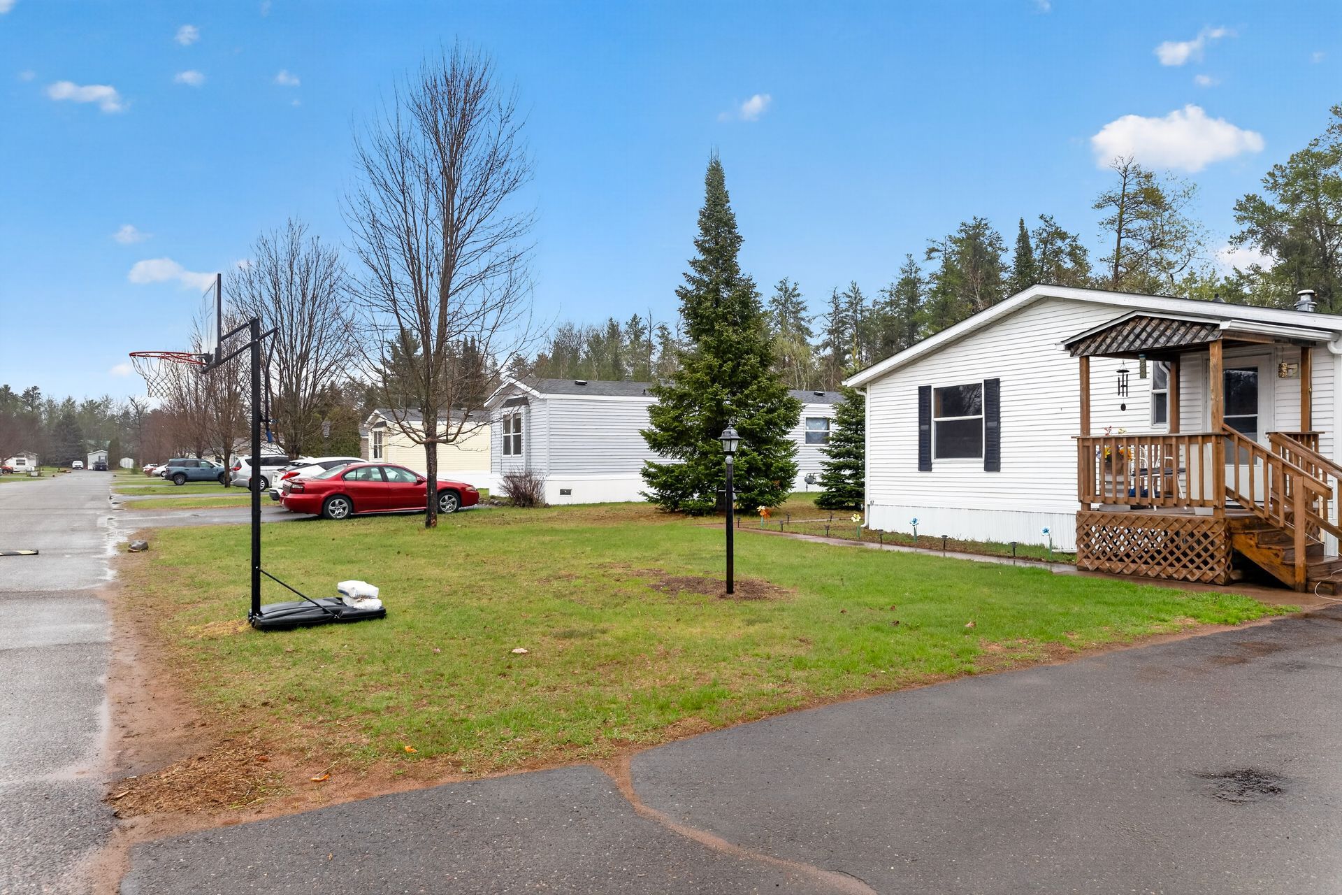 Mobile home park with white trailers, a red car, and trees under a blue sky