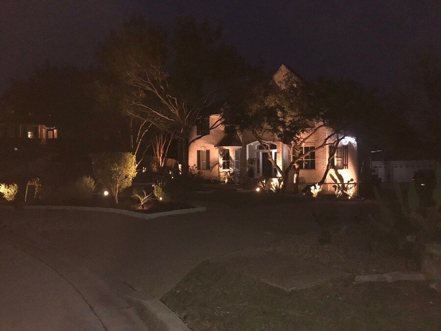 A house is lit up at night with trees in front of it