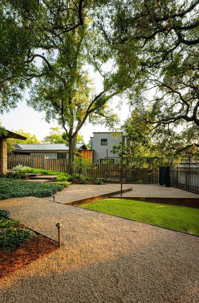 There is a gravel path leading to a house in the background.