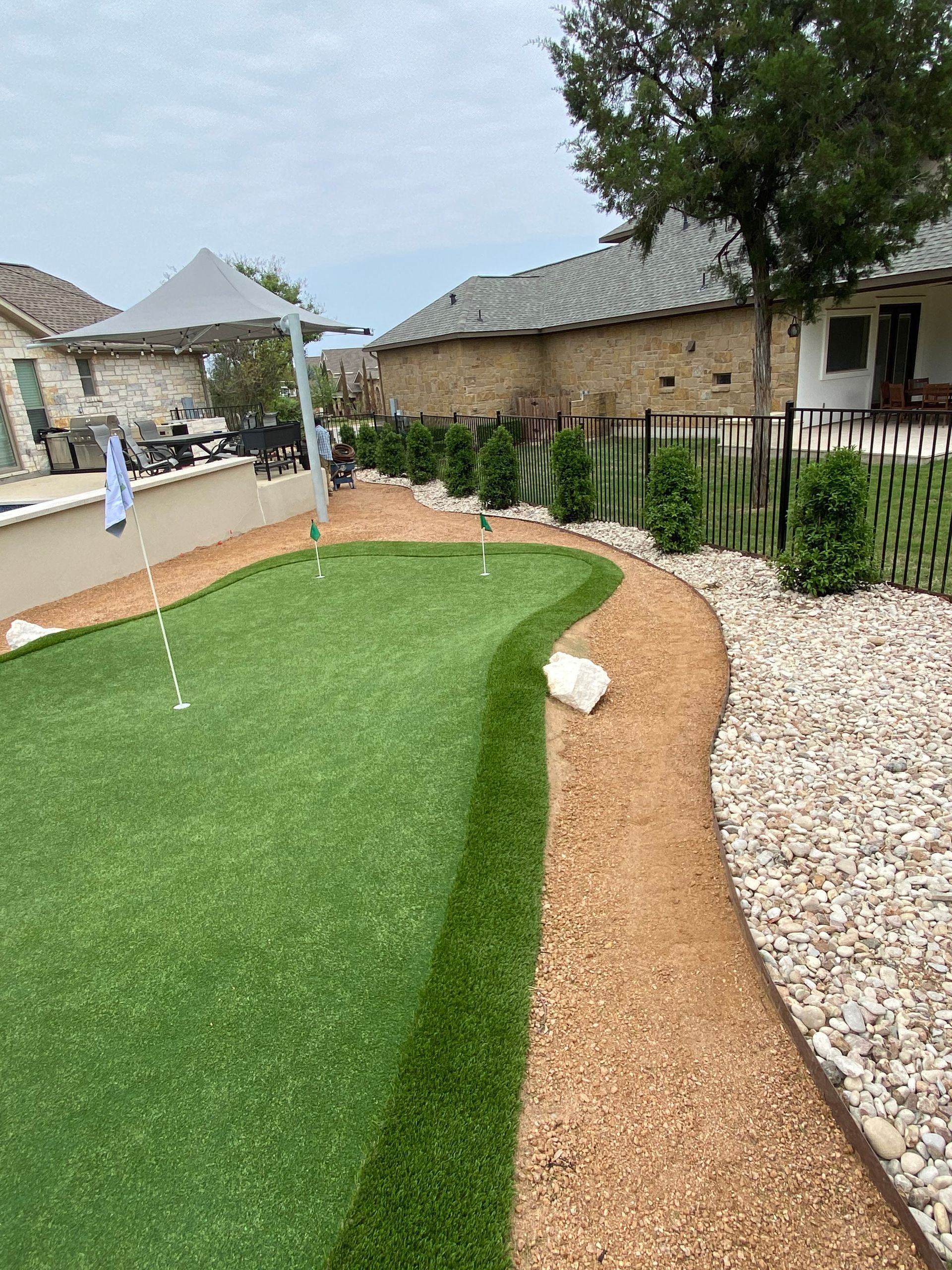 There is a putting green in the backyard of a house.