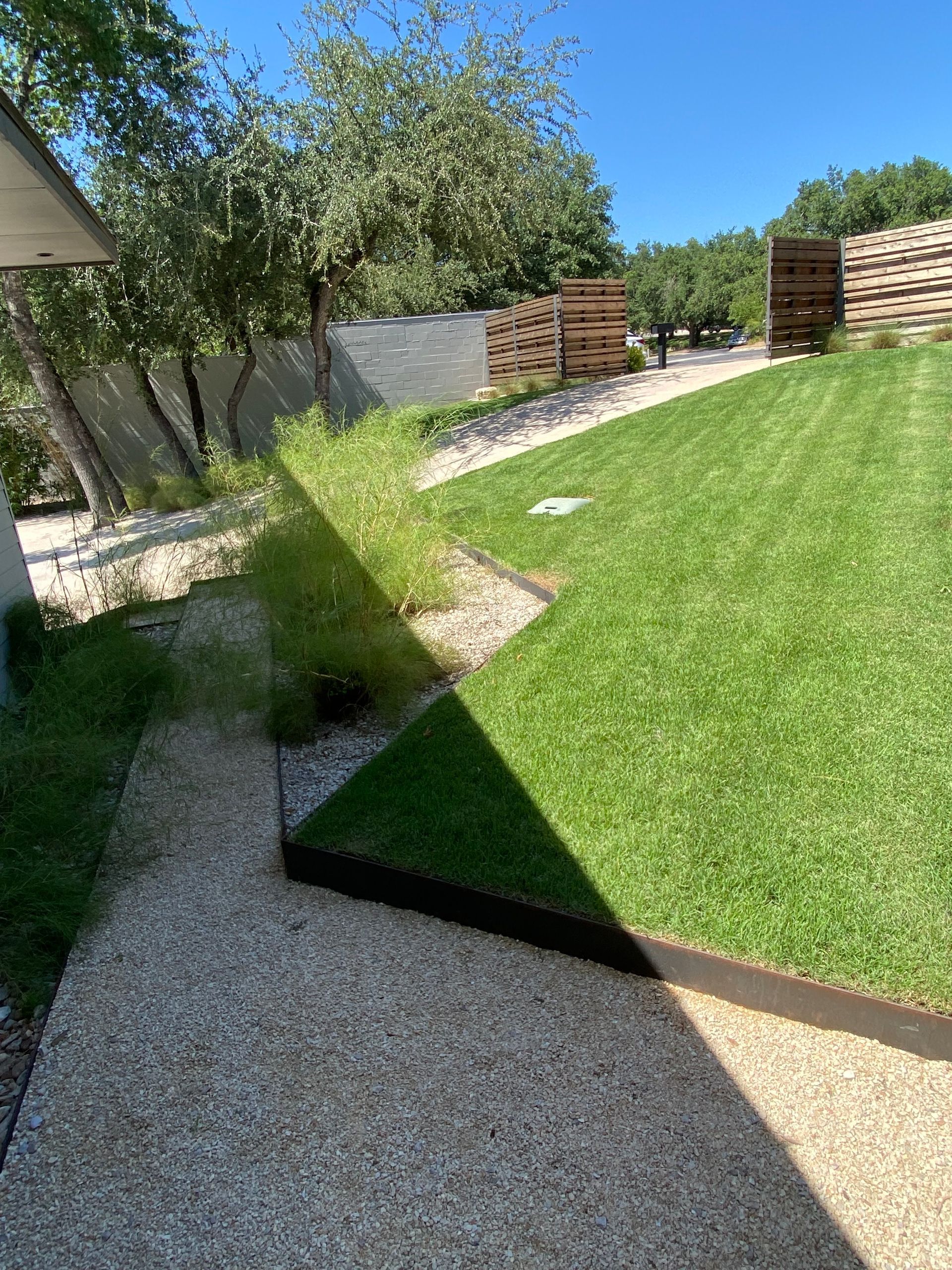 A lush green lawn with a gravel path leading to it.