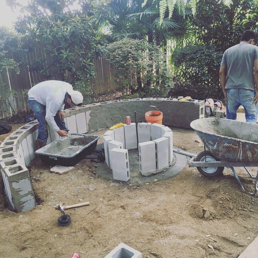 A man is working on a fire pit in a backyard