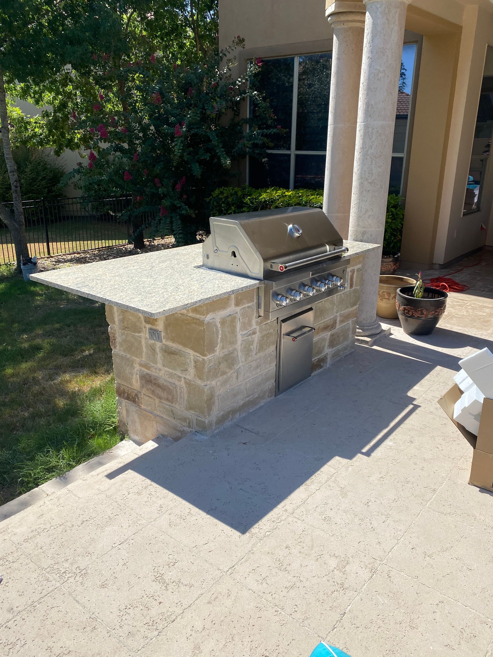 A grill is sitting on a patio next to a stone wall.