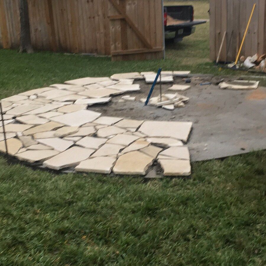 A circular stone walkway is being built in the grass