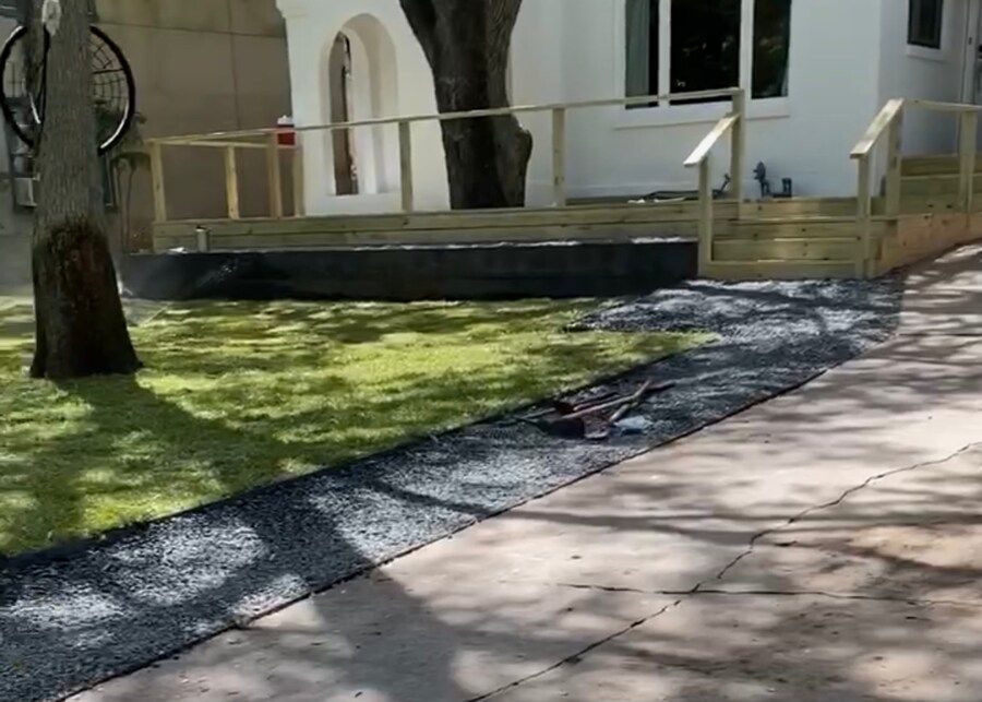 A lawn mower is sitting on the sidewalk in front of a house.
