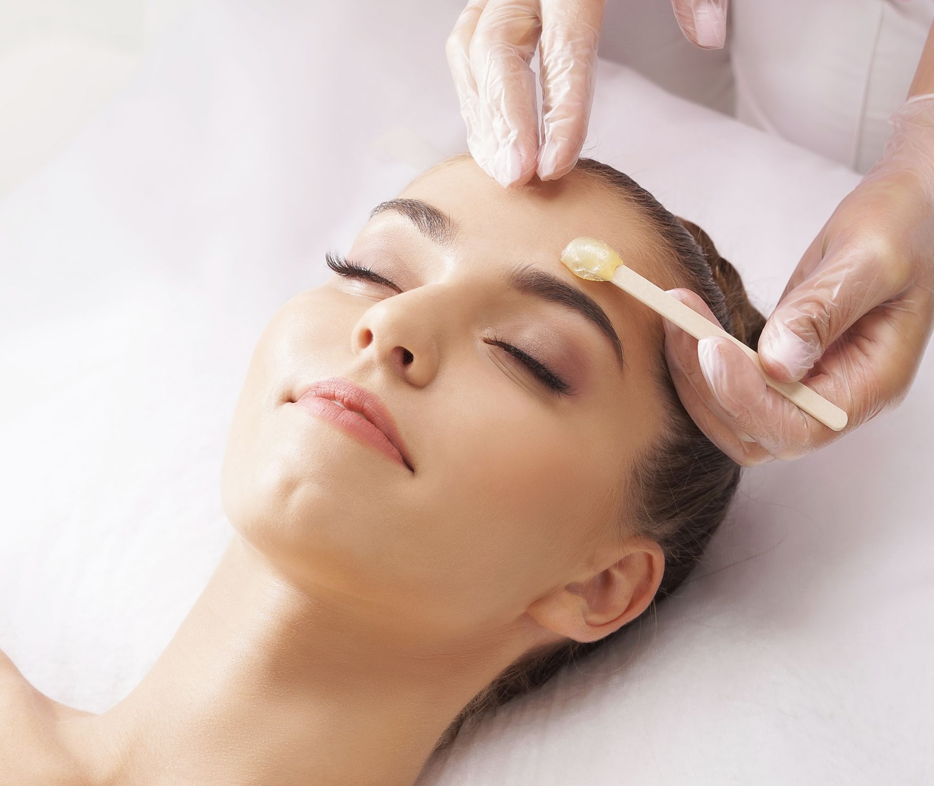 Woman receiving eyebrow waxing treatment