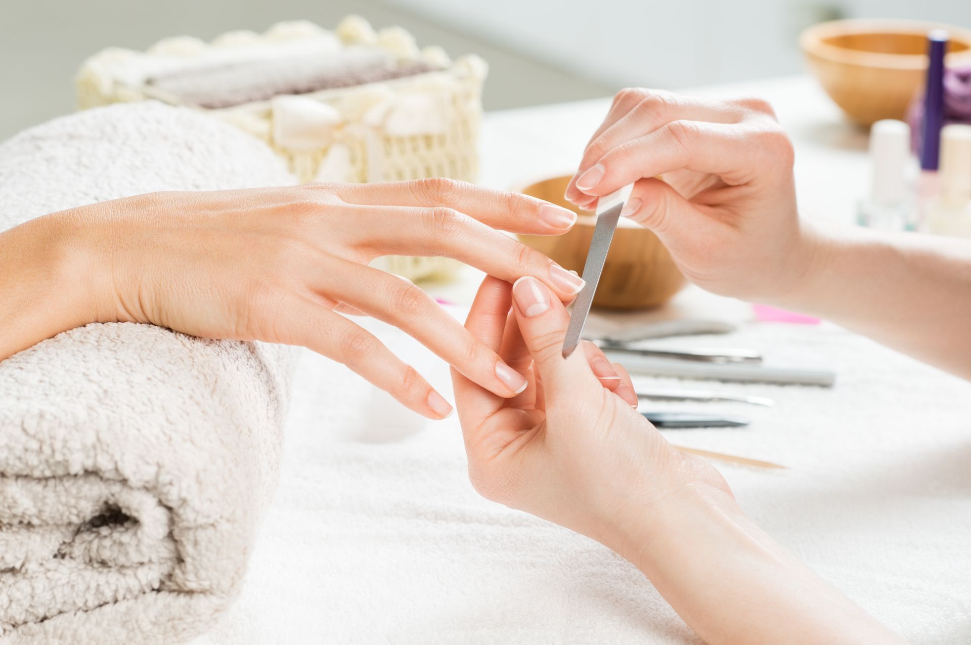 A person is filing another person's fingernail at a nail salon