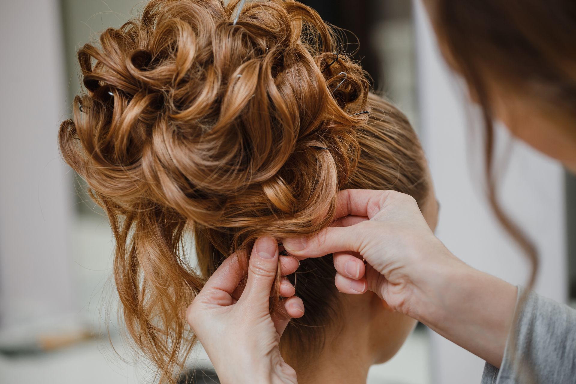Hands styling brown hair into an updo