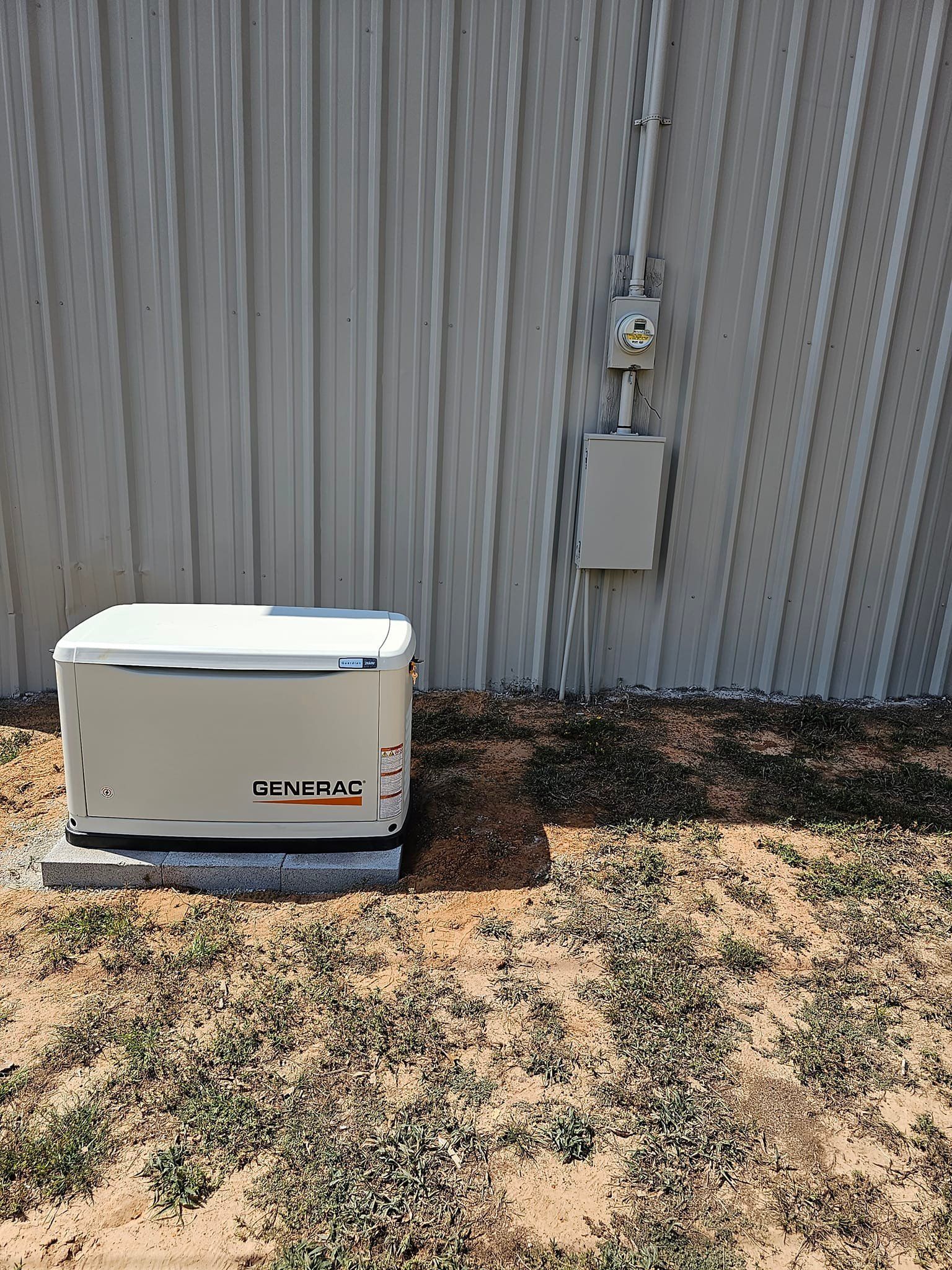 A generator is sitting in the grass in front of a building.