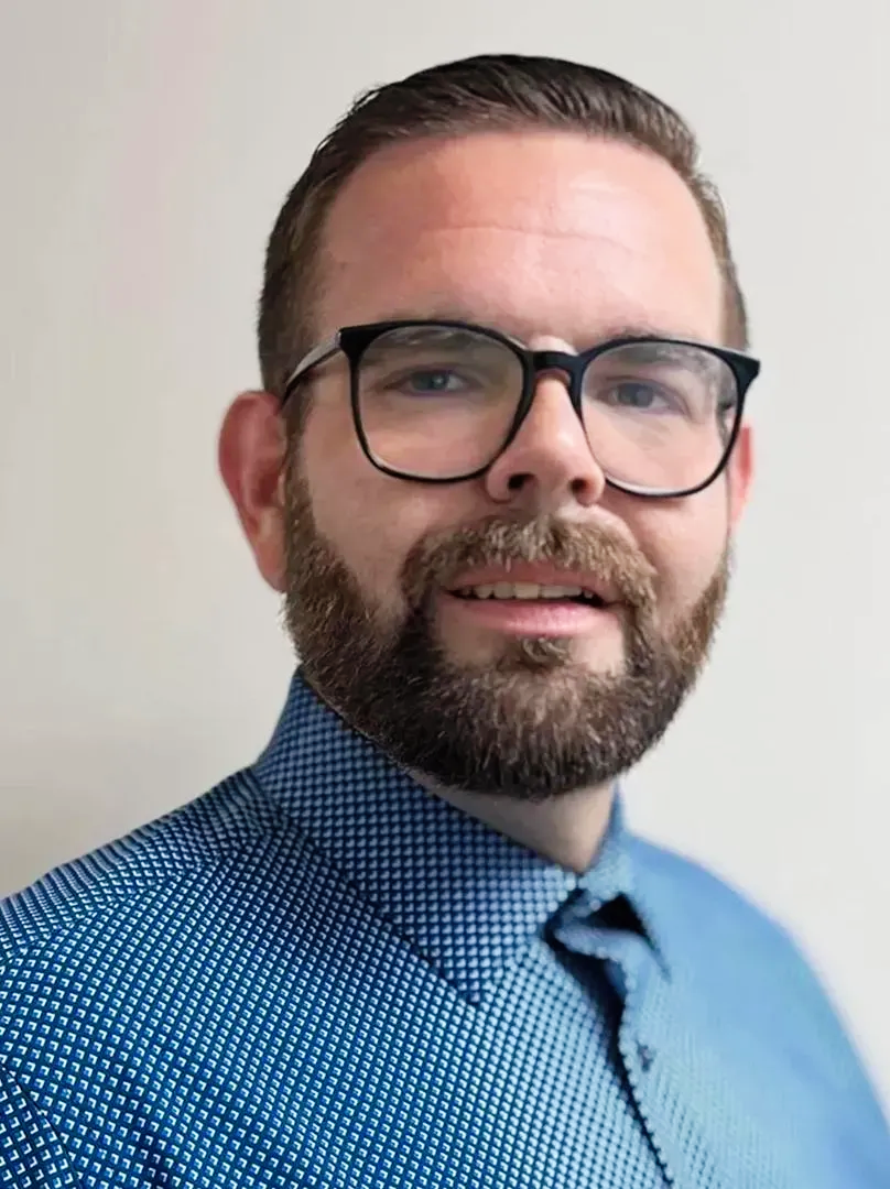 A man with a beard and glasses is posing for the camera