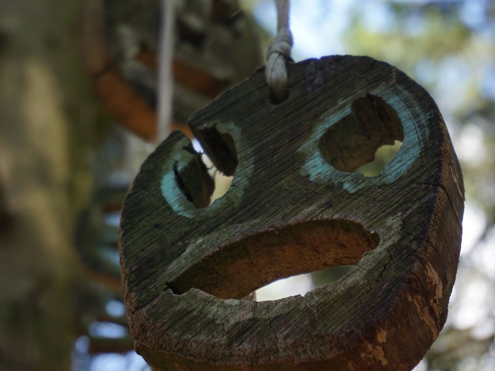 Eine Holzscheibe, die ein Gesicht zeigt. Auf dem Totenweg nach Wormbach