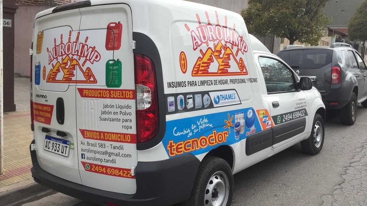 Una furgoneta de reparto blanca cubierta de coloridos anuncios de comida aparcada en una calle junto a un coche oscuro.