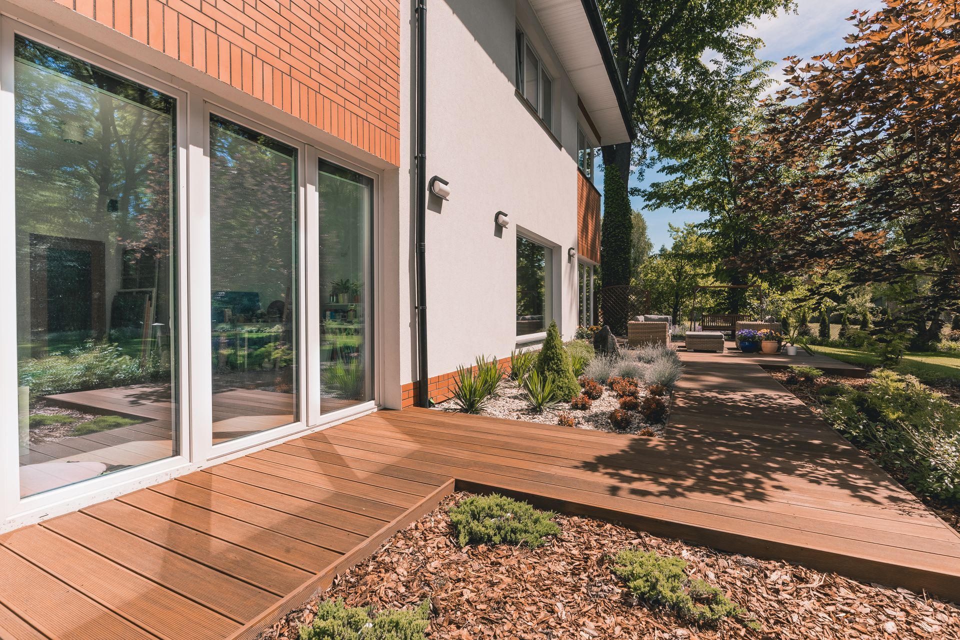 wooden deck pathway with landscaped trees alongside house wall