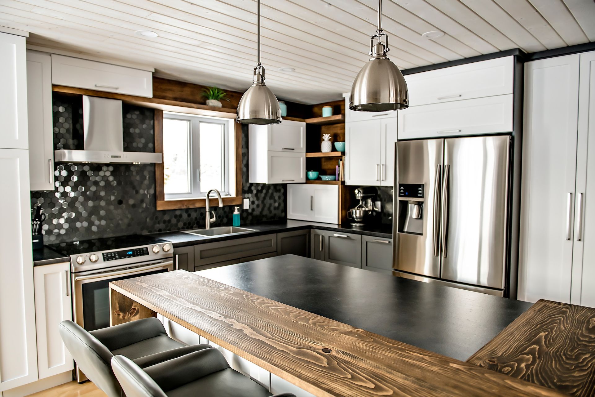 kitchen with stainless lighting and appliances with white cabinetry and combination dark oak and black quartz counters and island